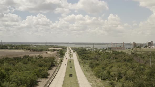 Cars drive on the road of a developing lake town. Street lights fill the frame.