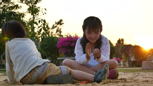 Asian Children Playing Sand In Playground Under Sunset