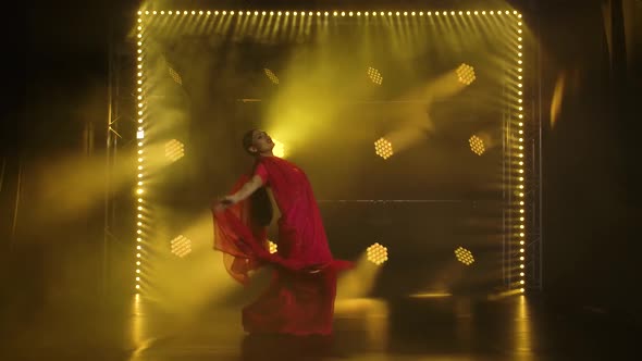 A Young Girl Dancer in a Red Sari. Indian Folk Dance. Shot in a Dark Studio with Smoke and Yellow