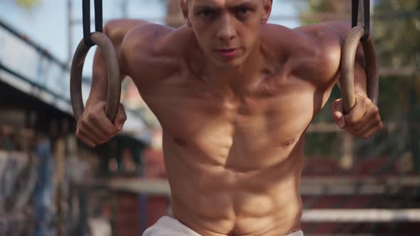 Muscular Athletic Young Man Exercising on Gymnastic Rings