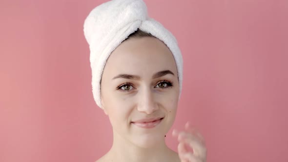 Plesant nude woman applying collagen eye masks on face in front of a mirror