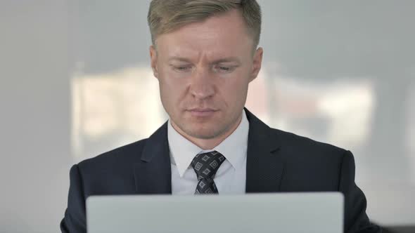 Close Up of Shocked Businessman Working on Laptop Frontal View