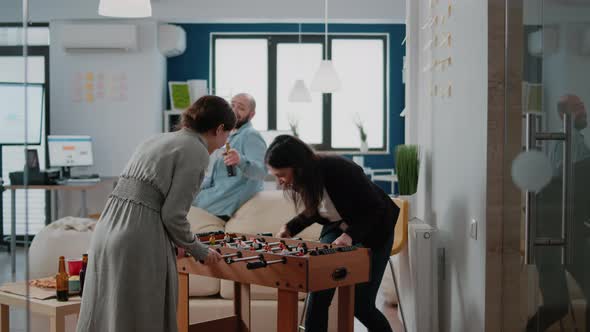 Women Playing with Foosball Game Table to Have Fun After Work