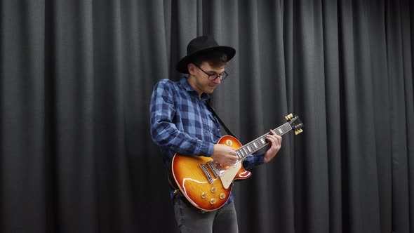 Musician Man Playing on Electric guitar wearing hat and blue shirt and glasses. Music concept