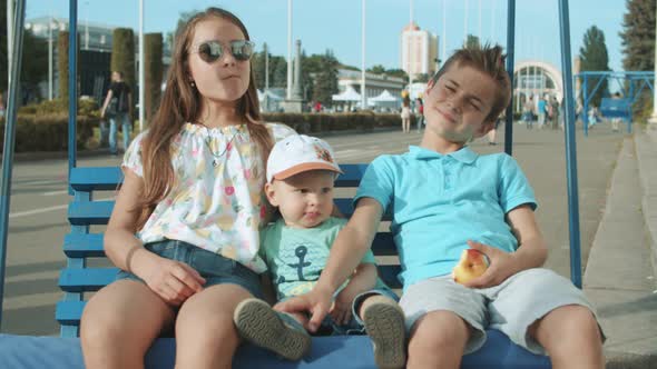 Relaxed Little Kids Sitting on Swing. Cute Three Siblings Spending Time Outdoors