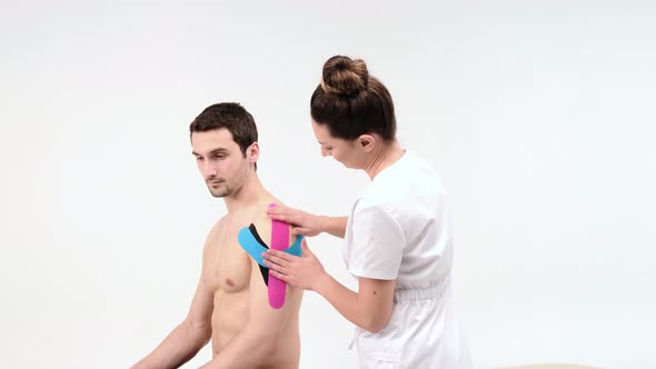 Shoulder treatment with kinesio tape. Physiotherapist applying elastic therapeutic tape