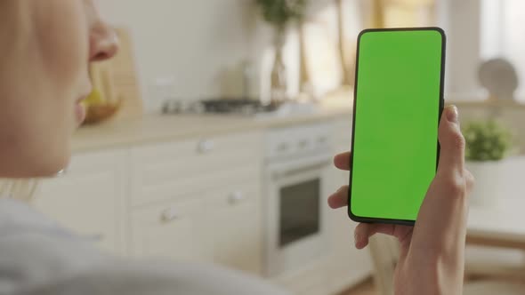 Back View of Woman Holding Chroma Key Green Screen Smartphone Watching Content Without Touching or