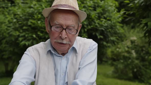 A Grandfather in Glasses and a Hat is Surprised By His Grandson's Stories