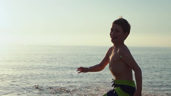 Boy Runs Merrily Through the Water Looks at the Camera and Smiles