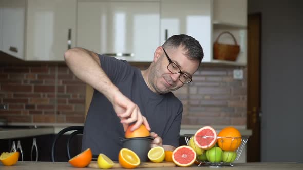 A Man Squeezes Orange Juice with Citrus Juicer