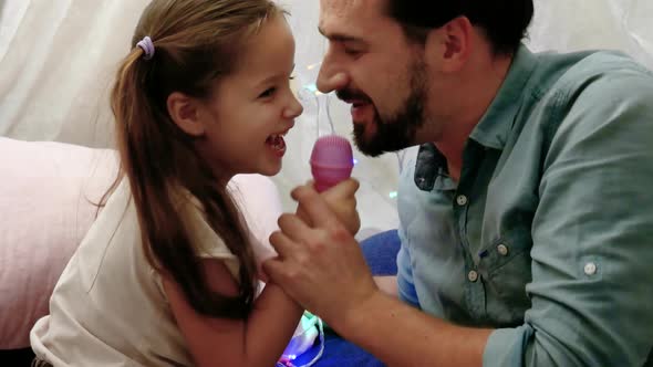 Father with Cheerful Little Daugher Singing in Microphone