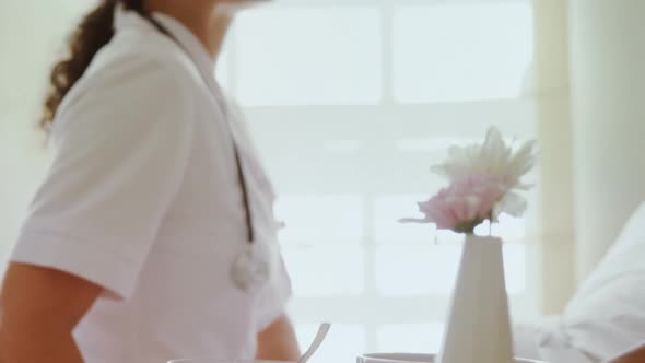 Female doctor serving breakfast to senior woman on bed