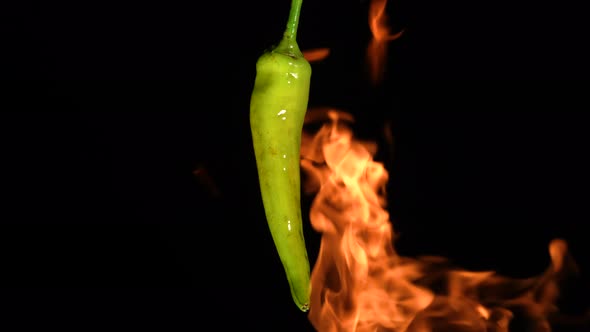 Green Hot Chili Peppers Roasting Over Fire on Black Studio Background