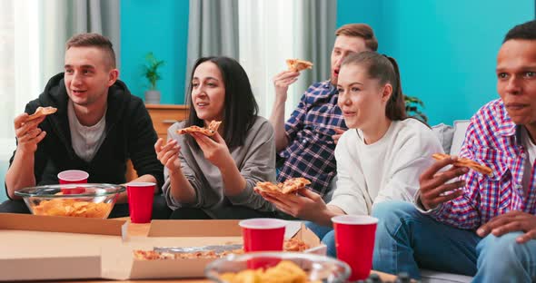 Joyous Multiethnic Friends are Eating Cheesy Pizza Chatting Relaxing During Indoor Party in