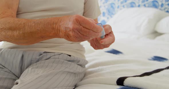 Front view of senior Caucasian man checking blood sugar level on bed in a comfortable home 4k