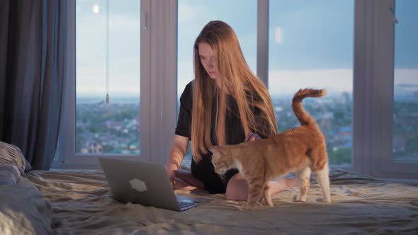 Young Cheerful Girl Student Using Laptop in Bedroom with Beautiful View