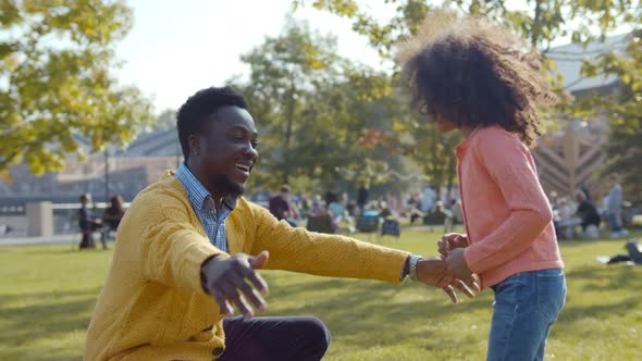 Side View of African Father and Daughter Giving High Five and Hugging Outdoors