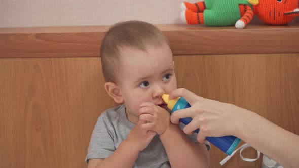 The mother's hand uses a nasal spray with sea salt in the nose of the daughter of 12-17 months