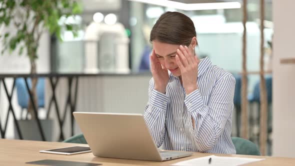 Stressed Woman with Laptop Having Headache in Office 