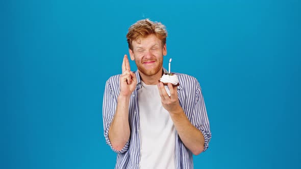 Young Redhead Man Makes Wish Blowing Out Candle on Cake