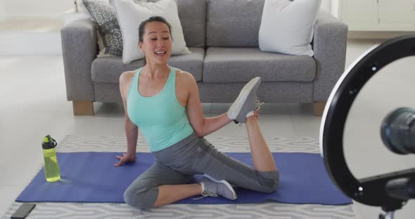 Happy asian woman on mat, exercising, making fitness vlog from home