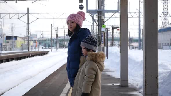 Asian Children Waiting Express Train On Railway Station Platform,Winter Travel Concept 