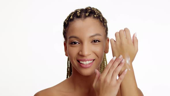 African American Female Applying Moisturizer On Hand Over White Background