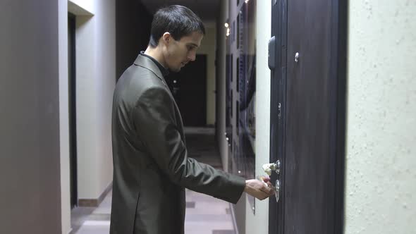 A Young Handsome Businessman Unlocks a House's Door with Key and Enters