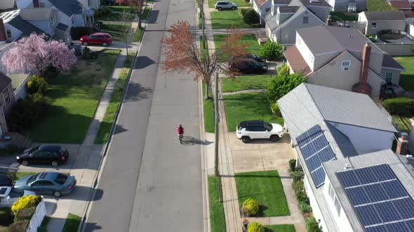 An aerial shot over a suburban neighborhood on a sunny day. The camera dolly in and tilt down over t