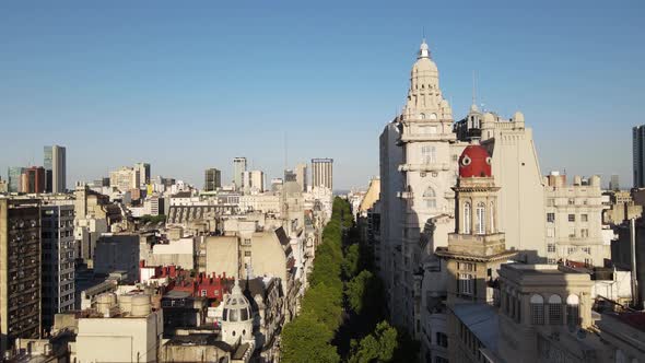 Aerial dolly in of tree-lined May Avenue and Barolo Palace tower at sunset in Monserrat neighborhood