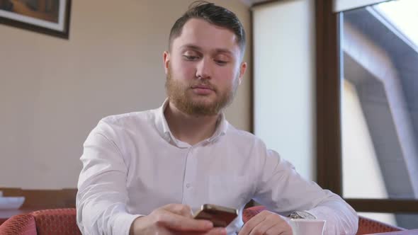 Young Handsome Man Using Smart Phone in Cafe