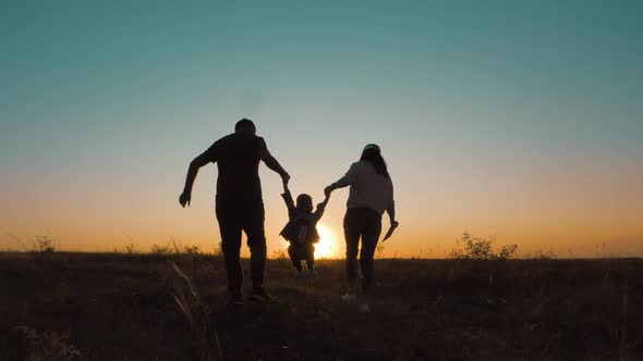 Happy Family Parents and Little Son Silhouettes Playing on Park