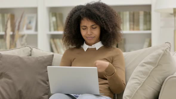 Young African Woman with Laptop Having Wrist Pain on Sofa