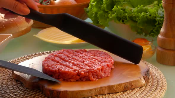 Cook Raises Cutlet for Hamburgers with Two Spatula