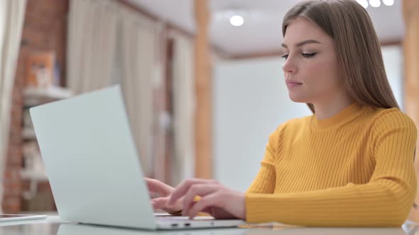 Creative Young Woman Working on Laptop and Smiling at the Camera