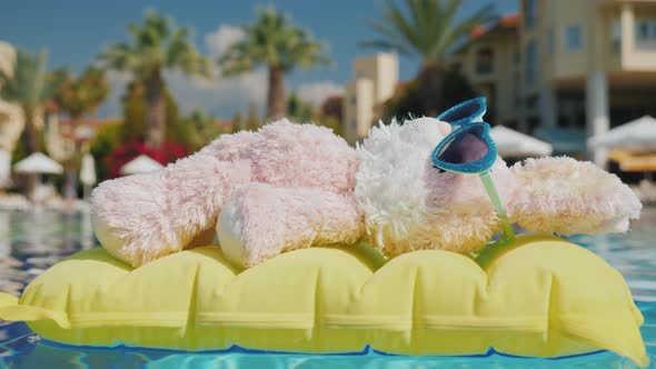 A Plush Bunny Floats on a Yellow Inflatable Mattress in the Pool. Rest with Children