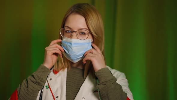 Happy Female Doctor or Nurse in Glasses Taking Off Medical Face Mask and Smiling