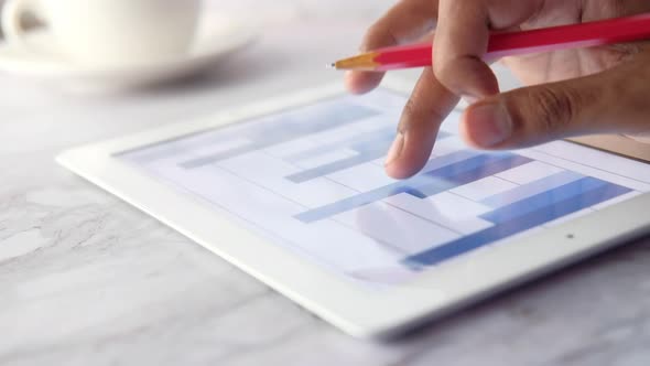 Man's Hand Working on Digital Tablet at Office Desk Using Self Created Chart