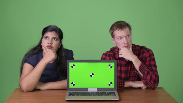 Young Multi-ethnic Business Couple Together Against Green Background