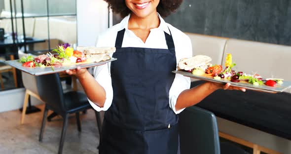 Portrait of smiling waitress holding food tray