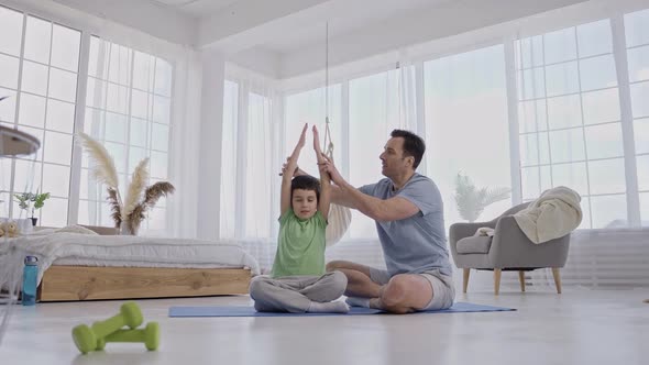 Caring Dad Helping Son to Keep Yoga Pose Indoors