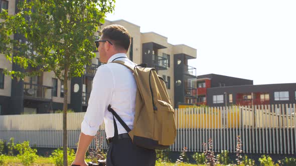 Businessman with Backpack Riding Electric Scooter