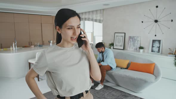 Young Hispanic Woman Talking On Phone In Living Room