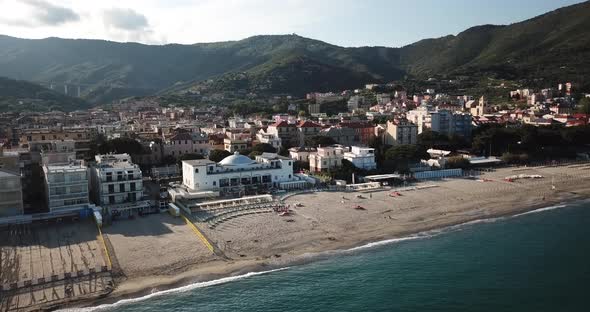 Sandy beach next to an italian mediterranean town. Aerial view during a sunset. Genoa