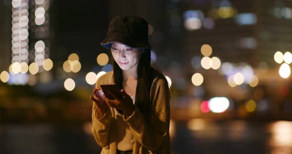 Woman use of smart phone in city at night