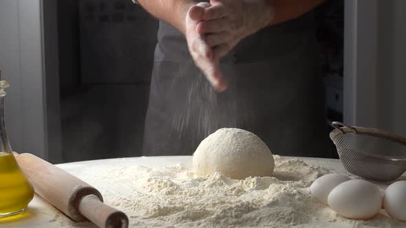 Baker Pours Flour on Dough for Pizza and Claping Hands with Flour