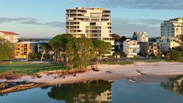 Panning along the shoreline as the calm mirror-like water reflects the buildings