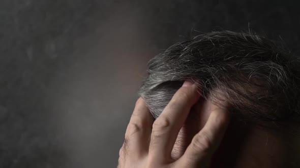 an Elderly Man Runs His Hand Through His Gray Hair