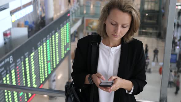 Businesswoman Using Mobile Phone And Checking Time At Smartwatch At Airport.