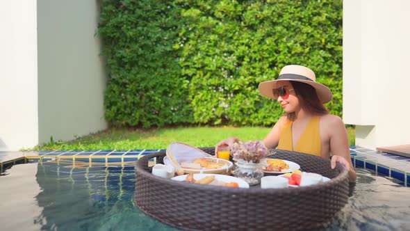 Woman with floating breakfast in pool